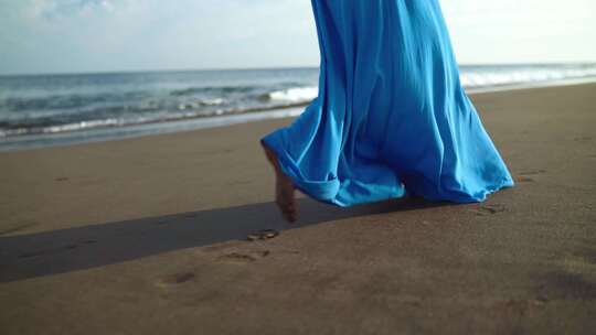 穿着蓝色裙子在海滩散步的女性