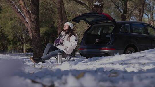 青年女人坐在雪地里喝热水