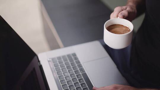 一边喝咖啡一边使用笔记本电脑的人