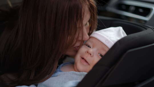 女人在汽车座椅上亲吻婴儿