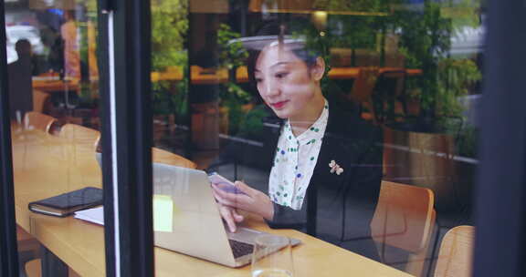 城市咖啡馆窗户边忙碌使用电脑办公的美女