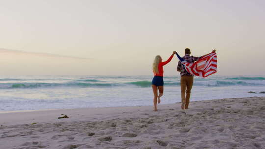一对夫妇在海滩4k举着美国国旗跑步