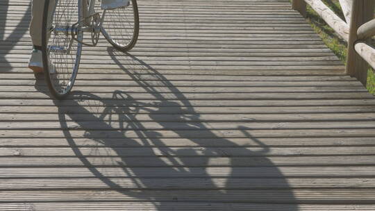 女人推着自行车在桥上的影子