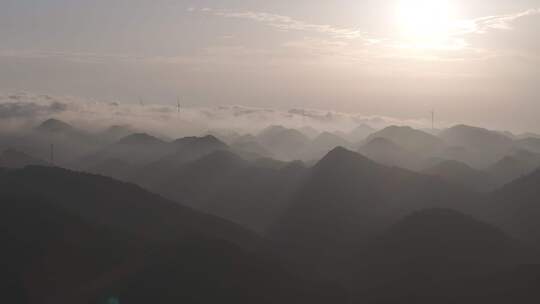 航拍大山顶上清晨云雾环绕日出风力发电风车