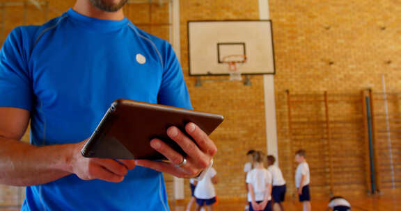 篮球教练在学校篮球场使用数字平板电脑4k