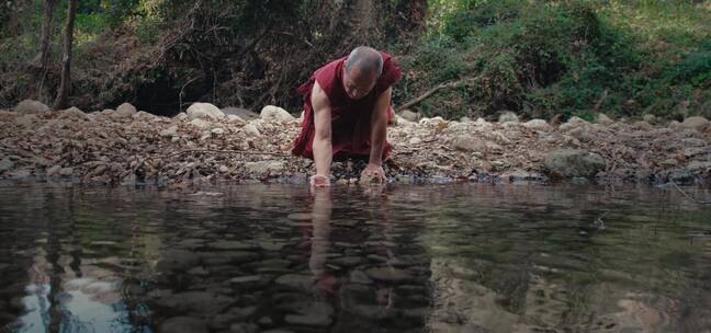 僧人在河边铲水