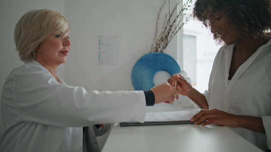 诊所病人在柜台特写女接待员协助下签署协议