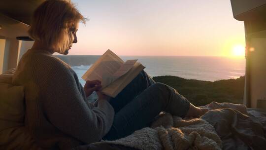 女人在海边的美丽风景下阅读视频素材模板下载