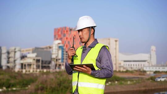 年轻工程技术人员手拿对讲机和图纸现场指挥视频素材模板下载