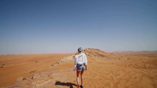 跟随一个走在沙丘上的年轻女人