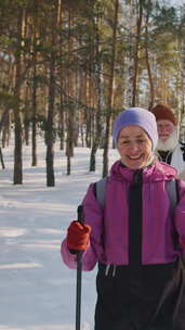 微笑的老人和女人在雪地里练习北欧行走