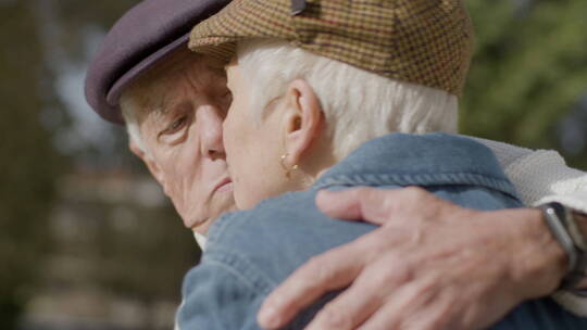 老年夫妻拥抱着在户外亲吻聊天