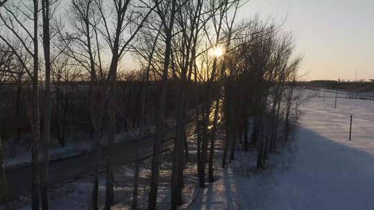 雪地公路迎着夕阳孤独行驶航拍