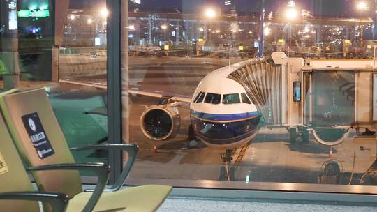 机场候机厅玻璃窗外停机坪上正在登机的客机