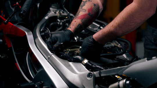 摩托车修理店的特写大师用螺丝刀拧开摩托车
