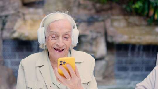 用耳机和手机听音乐的快乐老年妇女