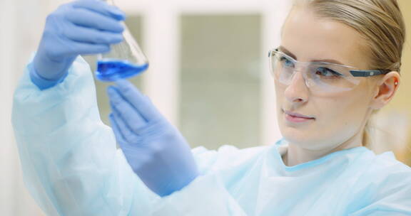 女科学家用玻璃器皿在实验室分析液体