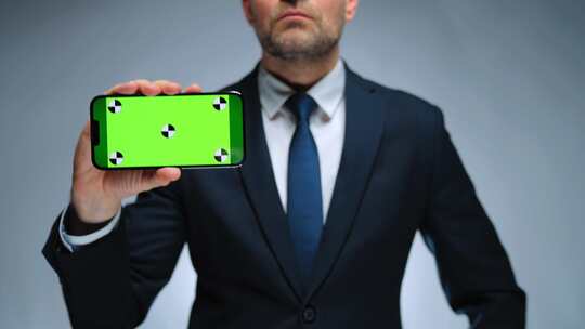 男子在相机上展示带有绿屏色度键的智能手机