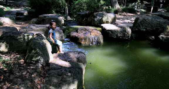 绿色森林山涧溪水水潭玩水的可爱中国女孩