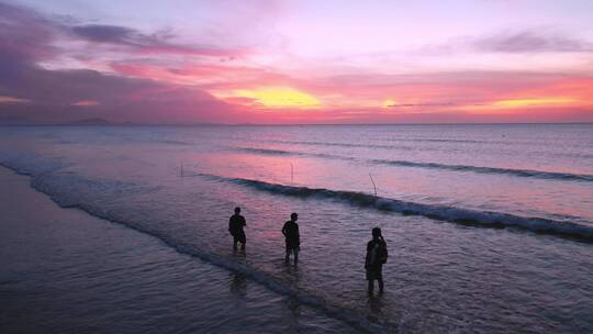 夕阳下海滩边三人背影