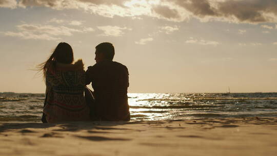 情侣坐在海滩上欣赏日落