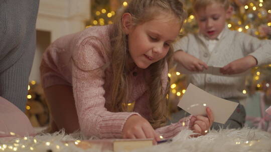 女孩趴着地毯上写圣诞卡片