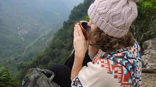 年轻女子旅行者在山顶喝茶