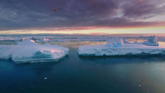 几座巨大的冰山漂浮在日落海洋中