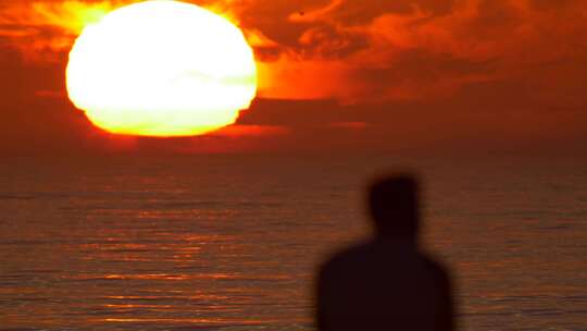 一个男人在海滩上看日落