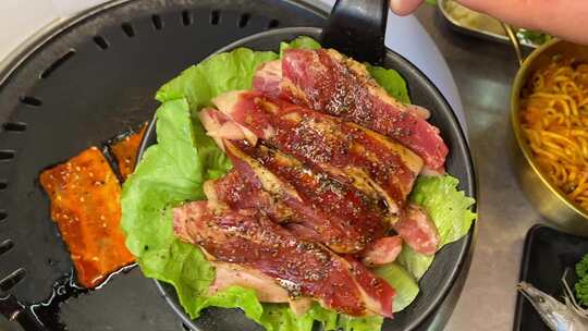 生菜上的烤肉，旁边还有一碗面条