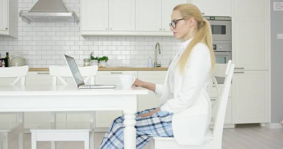 年轻成功的女性坐在家里的餐桌前使用笔记本电脑