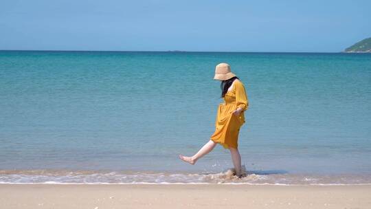 一个黄裙子美女在海边散步