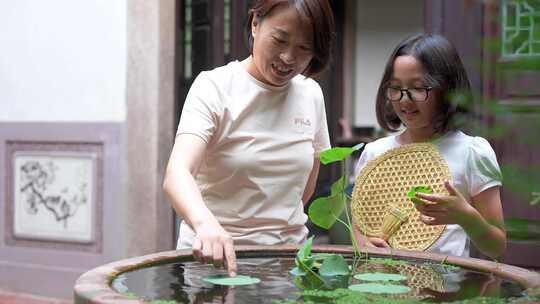 4K升格实拍坐在中式庭院纳凉观赏鱼的母女