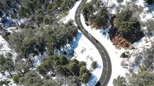 航拍冬天雪山汽车行驶在环山路上