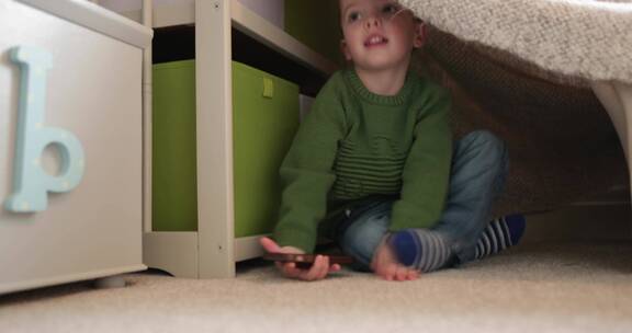 小男孩坐在帐篷里玩手机
