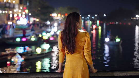 黄衣女子奥黛欣赏越南会安河边充满活力的夜