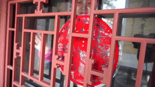 中式四合院胡同女人在贴窗花