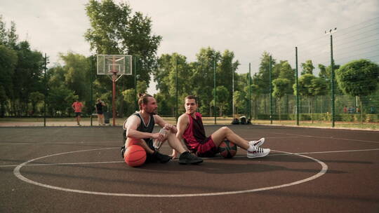 两个男人坐在篮球场上