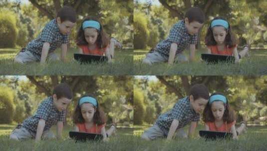 小孩在草地上玩平板电脑高清在线视频素材下载