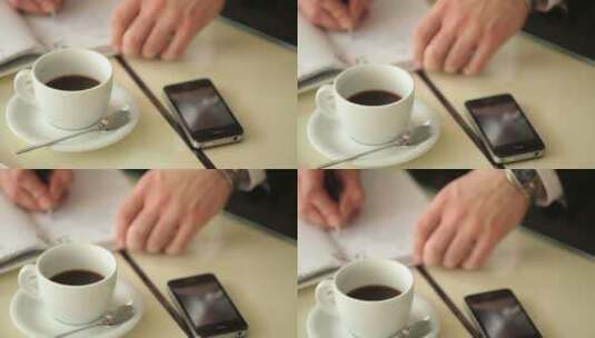 男子在放有咖啡和手机的桌子上写字高清在线视频素材下载