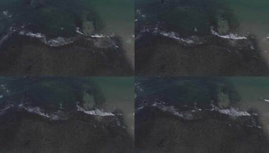 上帝视角下黑沙滩上海浪拍打着黑礁石高清在线视频素材下载