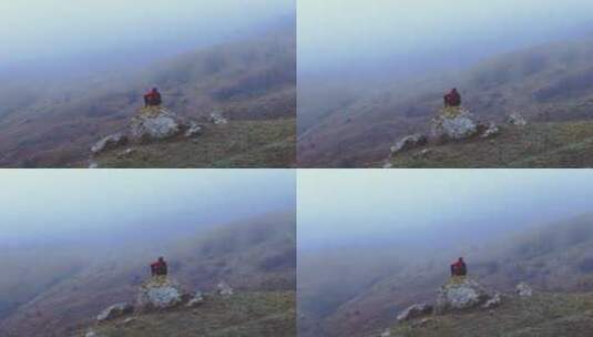 一个旅行者坐在山顶石头上高清在线视频素材下载