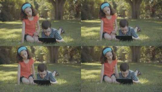 女孩和弟弟在草地上玩电脑高清在线视频素材下载