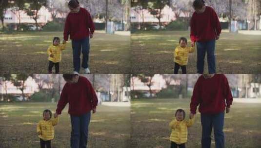 妈妈牵着小女孩的手走在公园草坪亲子户外高清在线视频素材下载