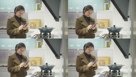中年女性在厨房使用手机高清在线视频素材下载