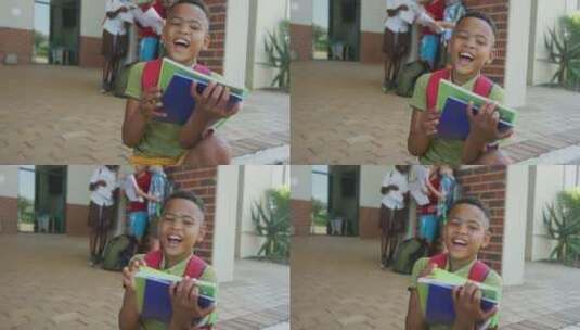 快乐的非裔美国男孩在学校前拿着书的视频高清在线视频素材下载
