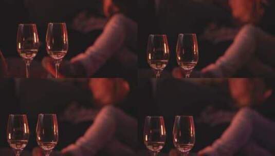两杯酒，背景是一对夫妇躺在沙发上高清在线视频素材下载