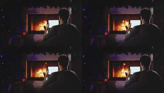 男人坐在壁炉旁的摇椅上玩电脑高清在线视频素材下载