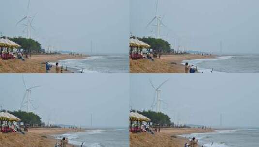 东方市鱼鳞洲沙滩上的游客与风力发电机高清在线视频素材下载