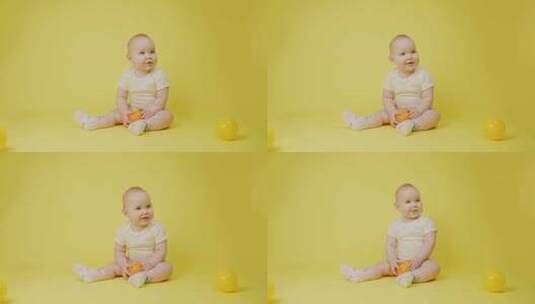 美丽的女婴抱着橙色坐在黄色背景的工作室里高清在线视频素材下载
